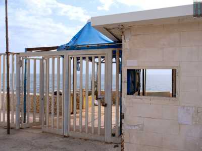 Entriamo ora nel lido varcando un cancello, (il cui celeste � stato divorato dalla ruggine), affiancato dalla finestrella della reception che ci regala un nostalgico scorcio vista mare